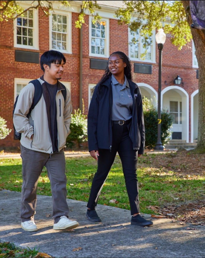 Two students walking in front of the Wiggs Office Building in MGA's Cochran campus